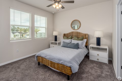 A bedroom with a bed, two lamps, and a ceiling fan.