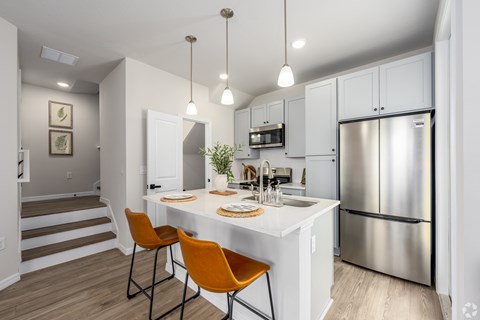 A modern kitchen with a white island and stainless steel appliances.