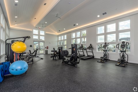 A spacious gym with various exercise equipment and large windows.