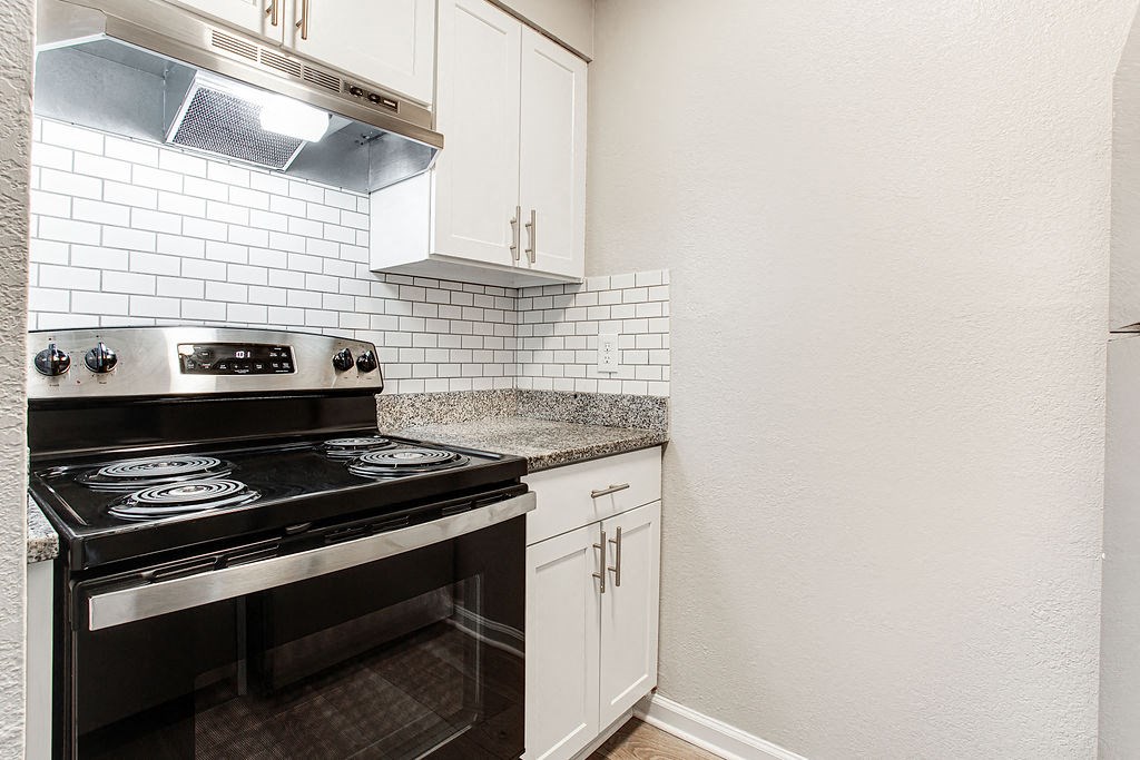 a kitchen with white cabinets and black appliances at The Ellis Apartments, Clarkston