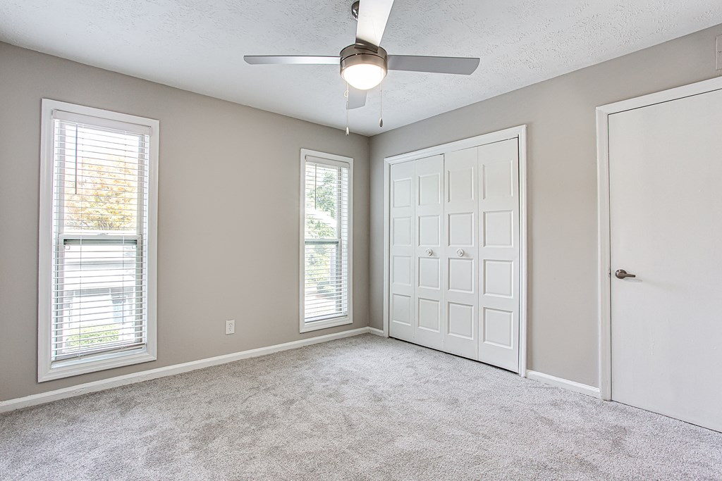 an empty room with a ceiling fan and two windows at The Ellis Apartments, Georgia, 30021
