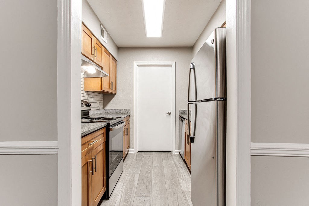 a kitchen with wood cabinets and stainless steel appliances at The Ellis Apartments, Clarkston, GA, 30021