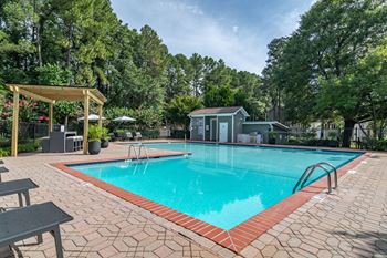a swimming pool with a gazebo and picnic table next to it