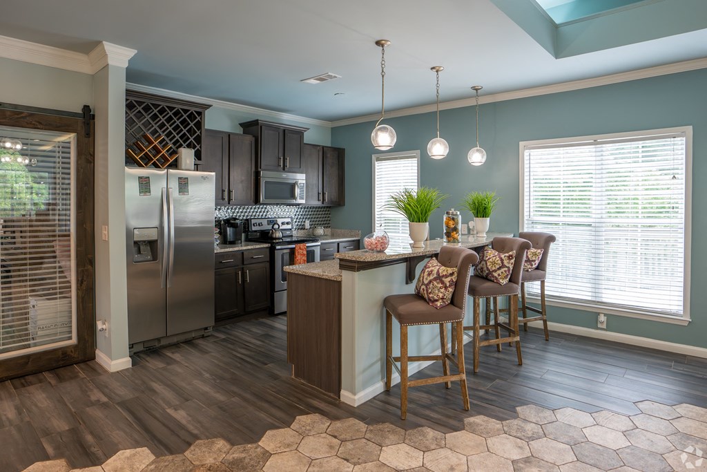 a kitchen with stainless steel appliances and a bar with chairs
