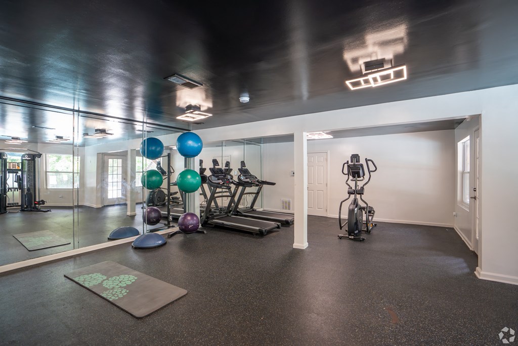 a fitness room with exercise equipment and mirrors on the wall