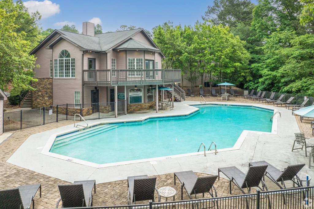 a pool with chairs and a house with a resort style pool