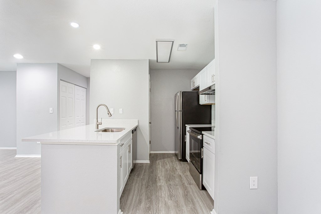 a renovated kitchen with white cabinets and a black stove and refrigerator at Parc at 1875, College Park