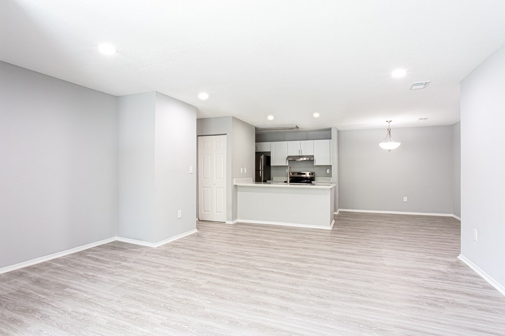 an empty living room with a kitchen in the background at Parc at 1875, College Park, Georgia