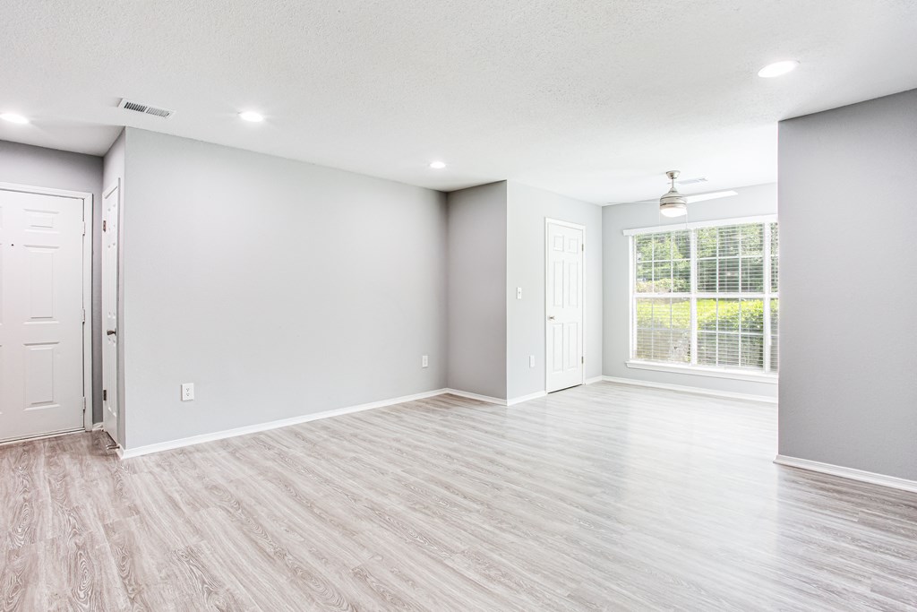 an empty living room with white walls and a window at Parc at 1875, College Park, Georgia