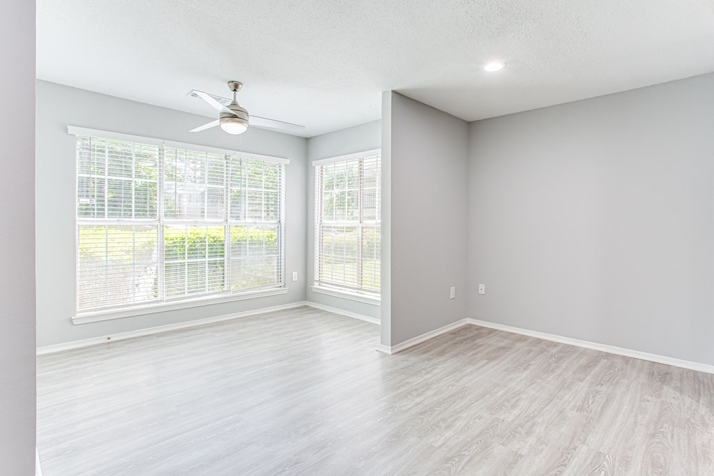 an empty living room with windows and a ceiling fan at Parc at 1875, College Park, GA