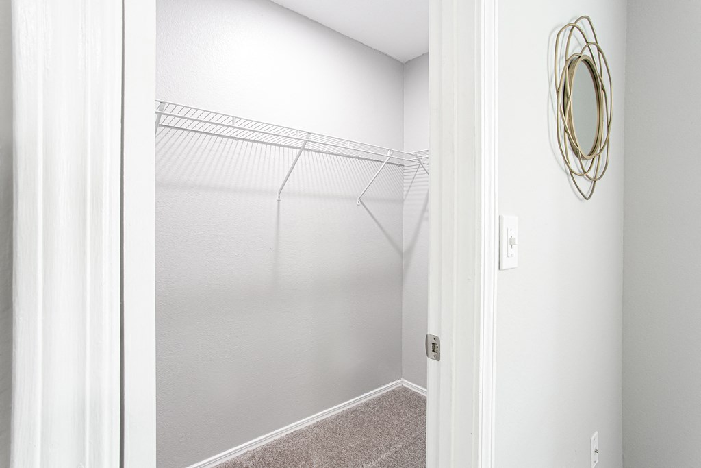 a walk in closet with white walls and a mirrored closet door at Parc at 1875, College Park, GA