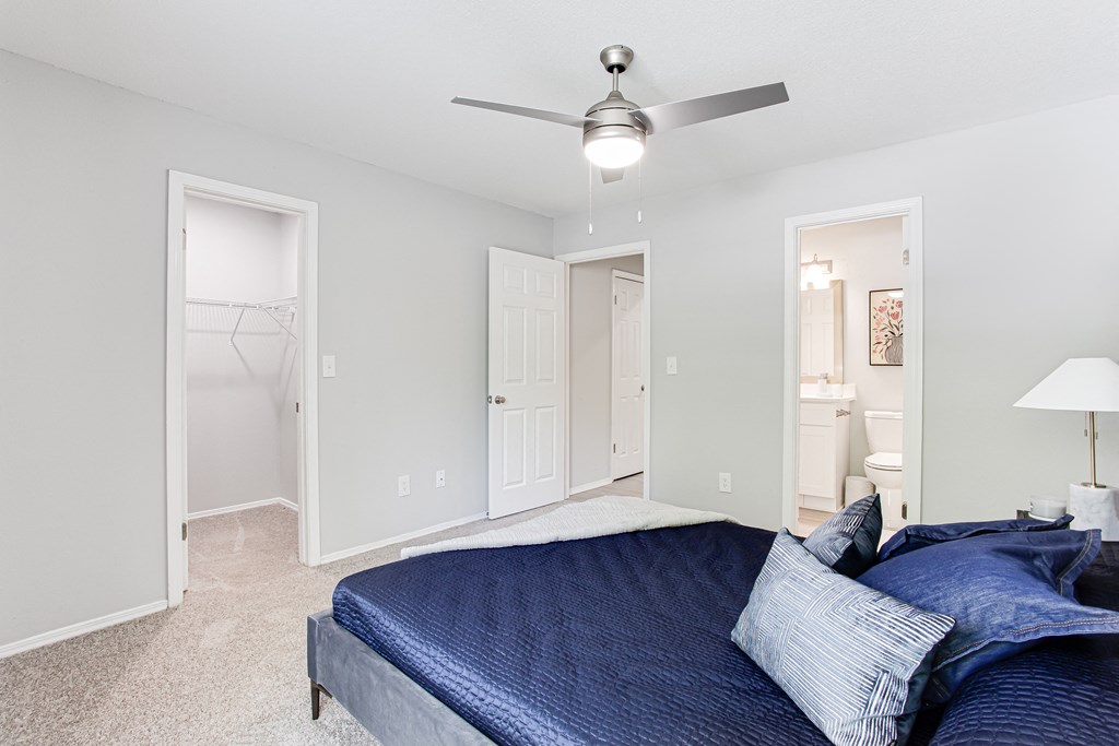 a bedroom with a blue bed and a ceiling fan at Parc at 1875, College Park