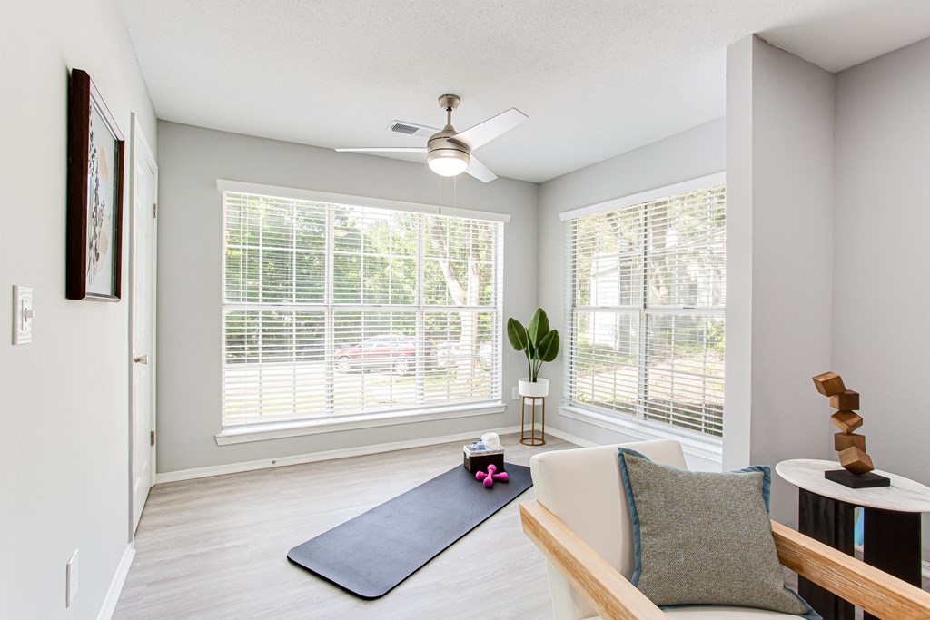 an empty living room with a yoga mat and a ceiling fan at Parc at 1875, College Park