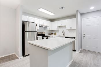 a white kitchen with a large island and stainless steel appliances