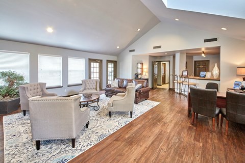 A living room with a white rug and wooden floors.