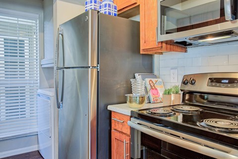A kitchen with a stainless steel refrigerator and a stove top oven.