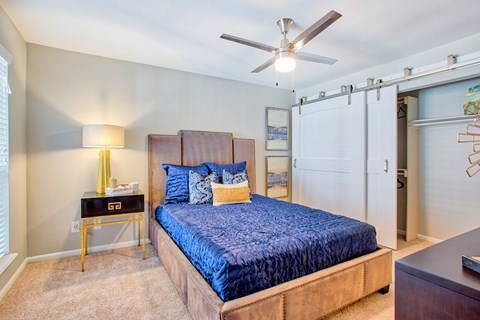 A bedroom with a bed, nightstand, and a ceiling fan.