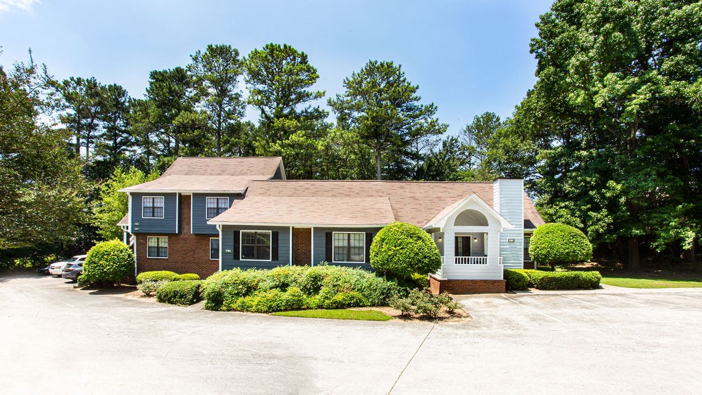 a house with a driveway and trees in the background