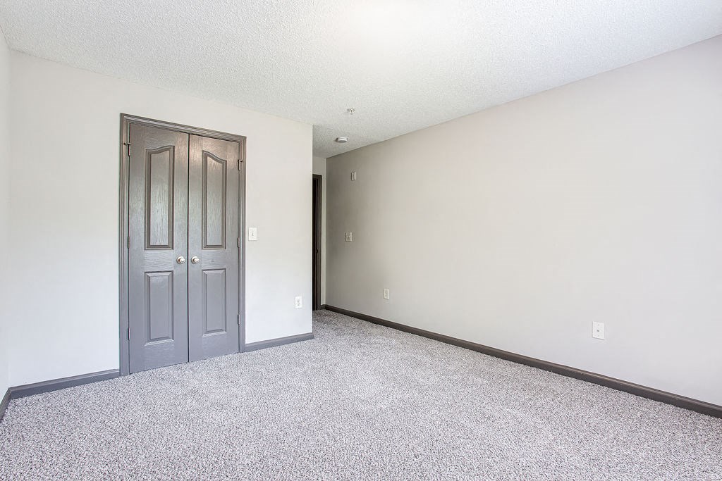 a bedroom with a door and a carpeted floor