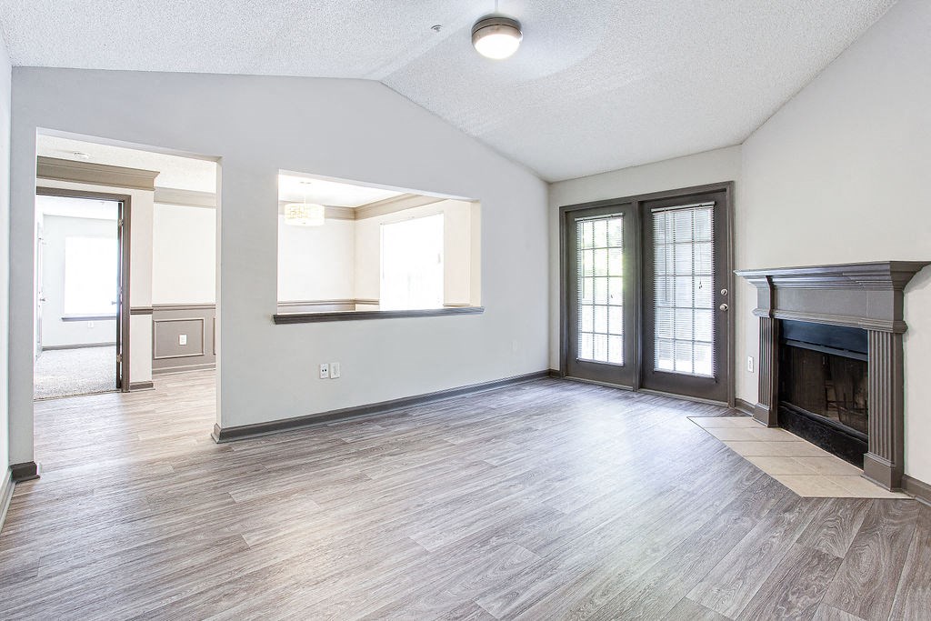 an empty living room with a fireplace and french doors