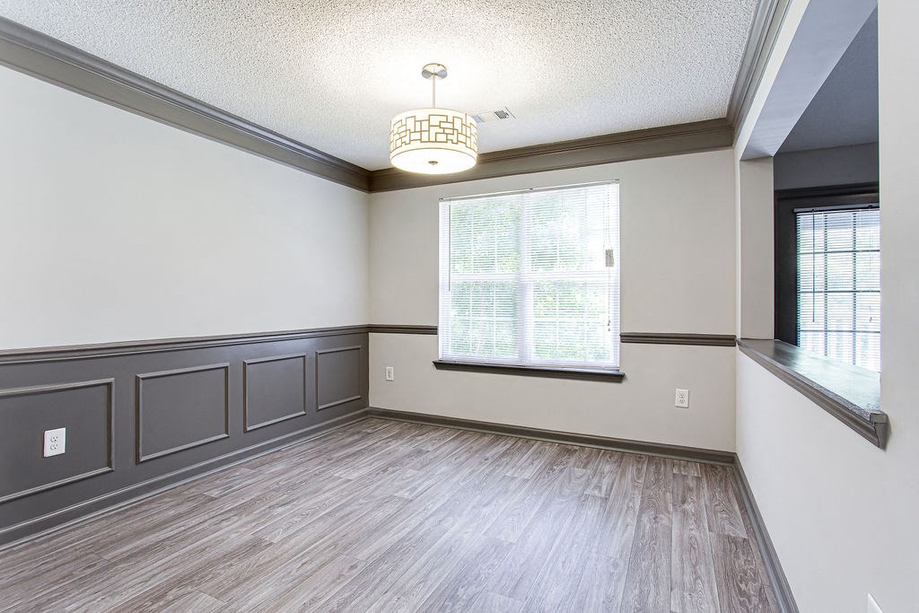 an empty dining room with gray walls and a chandelier