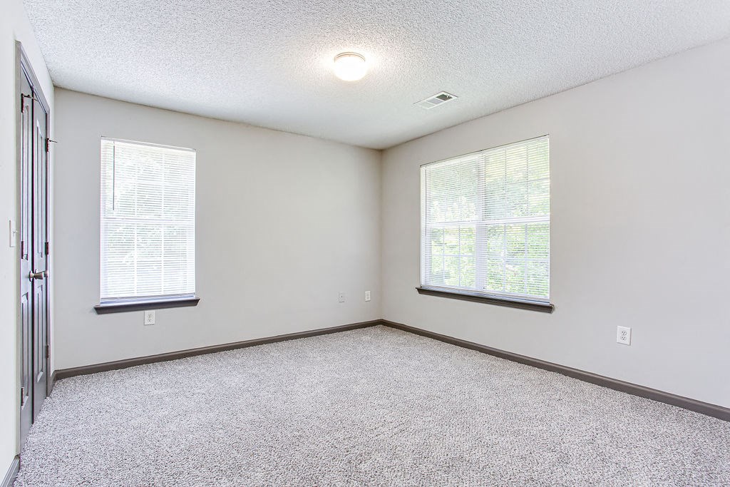 an empty room with two windows and a door