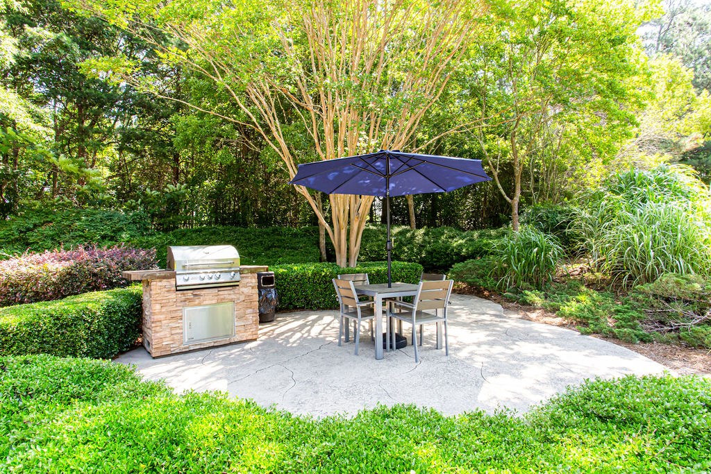 a patio with a grill and a table and chairs