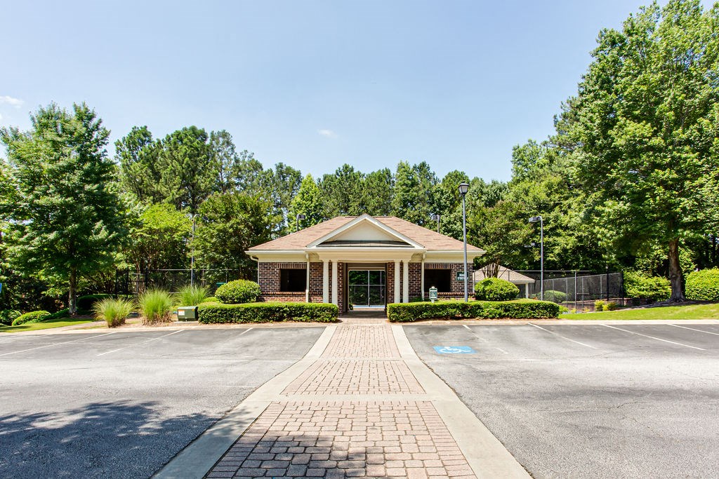 a parking lot in front of a brick building with trees in the background