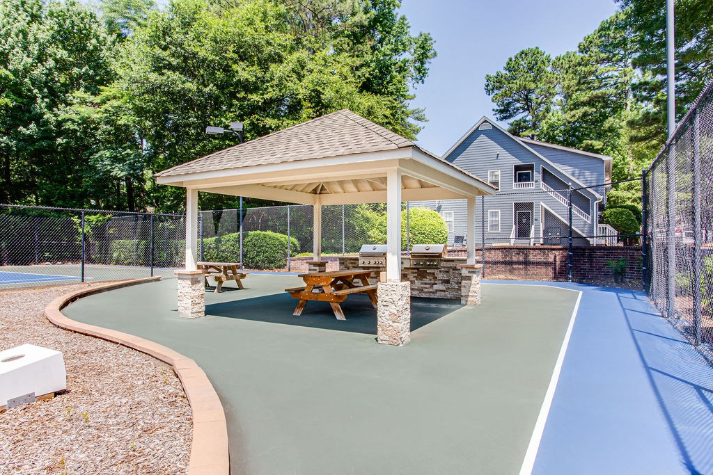 a backyard tennis court with a pavilion and picnic table
