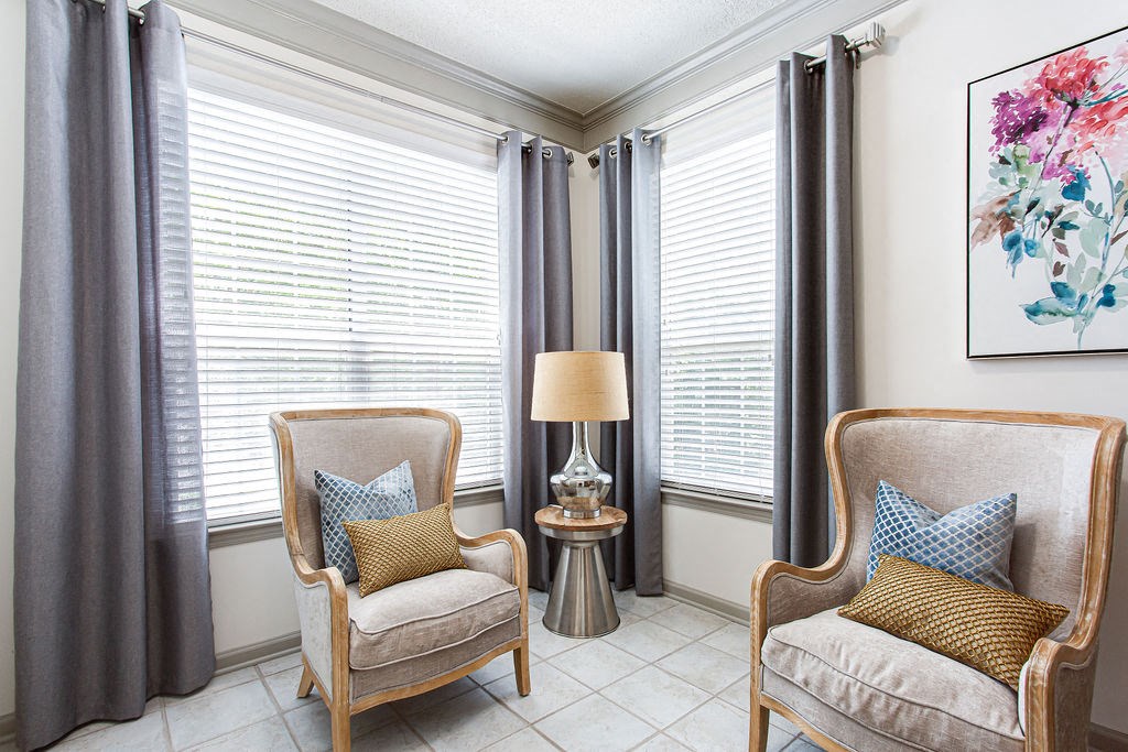 a seating area with two chairs and a table with a lamp