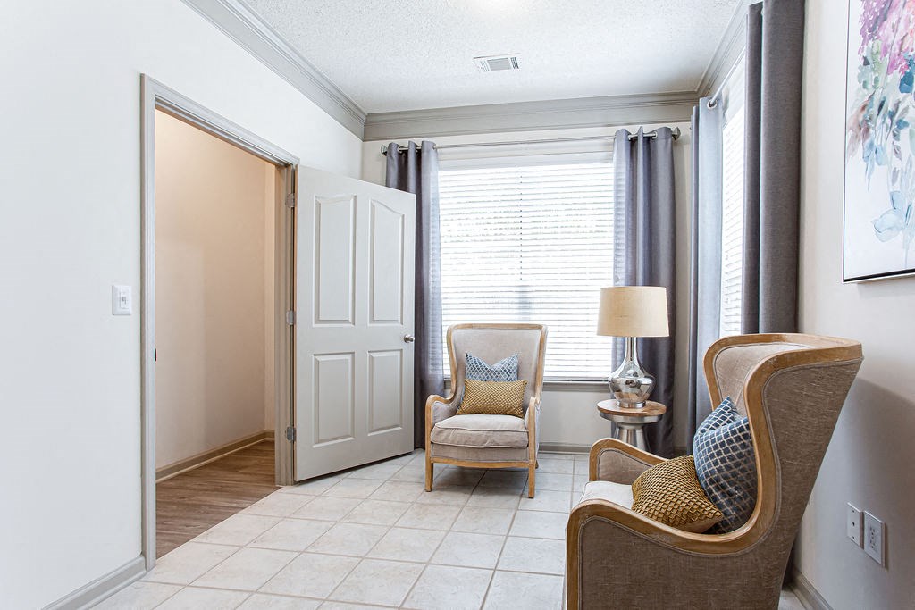 a living room with two chairs and a table with a lamp