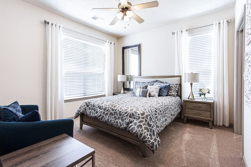 a bedroom with two windows and a ceiling fan