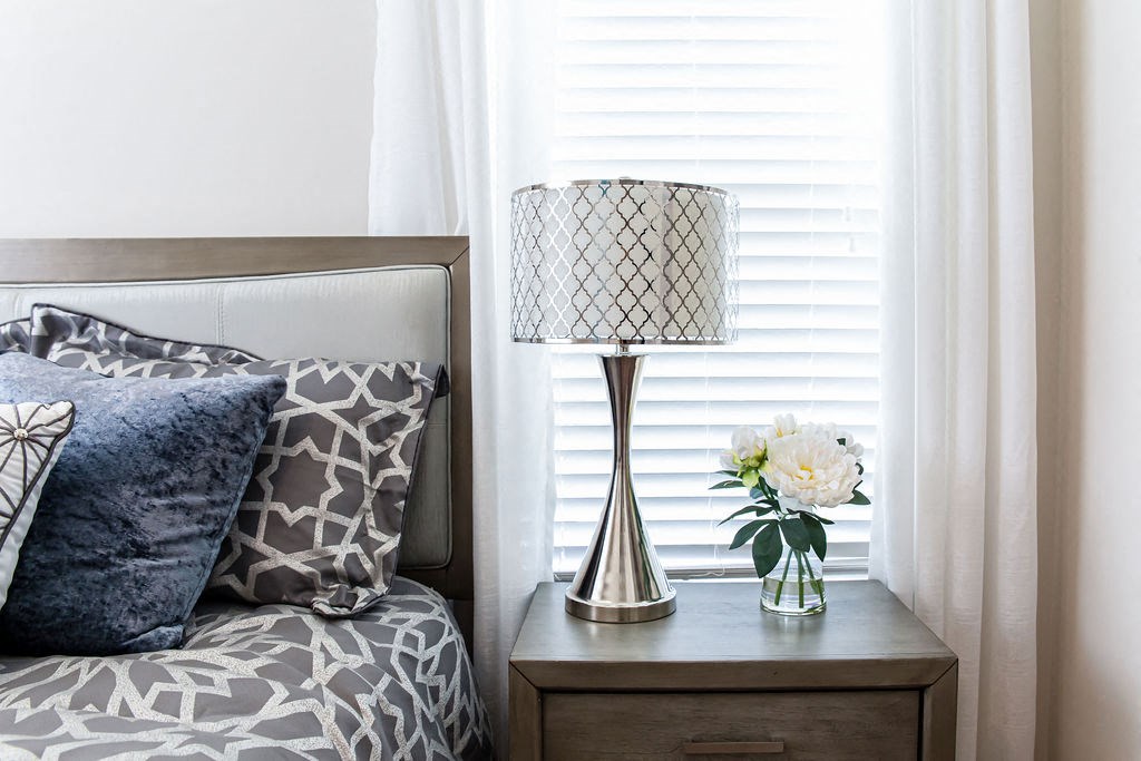 a bedside table with a lamp and a vase of flowers on it