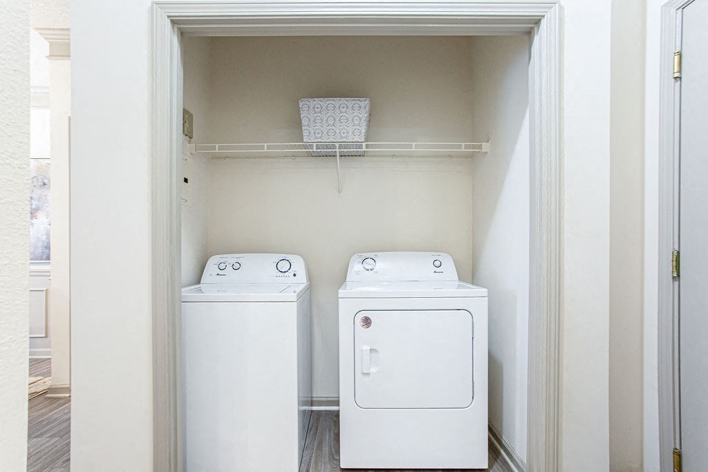 a small laundry room with a washer and dryer and a shelf above the washer