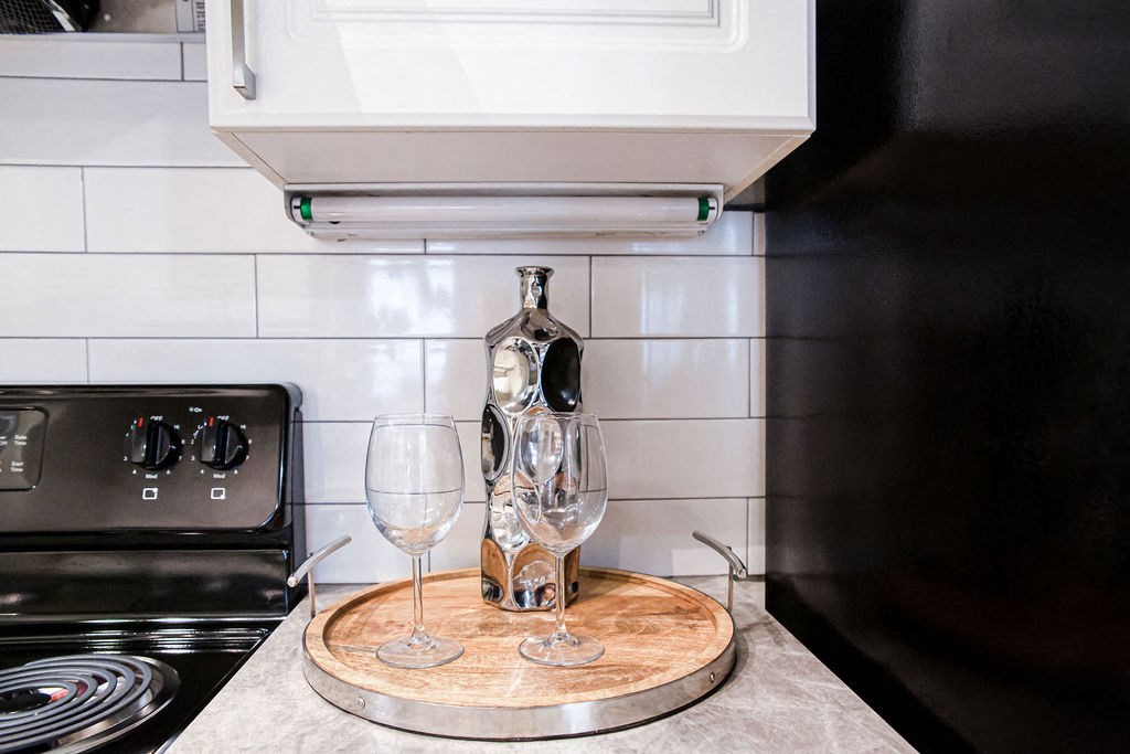 a bottle of wine and two wine glasses on a wooden board in a kitchen