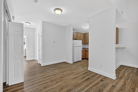 A kitchen with white walls and wooden floors.