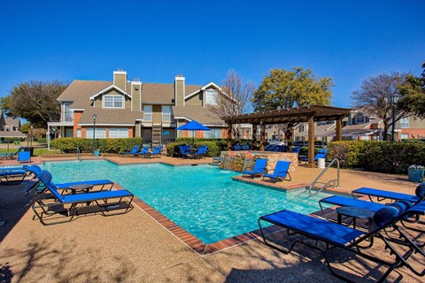 A pool with blue chairs and a building in the background.