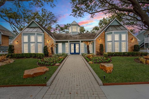 A house with a blue door and windows is surrounded by a well-manicured lawn.