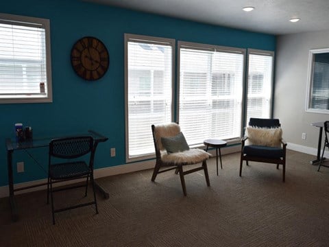 a living room with chairs and a table and a clock on the wall