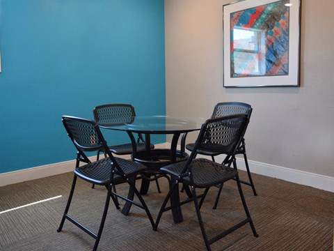 a dining room table with four chairs and a painting on the wall