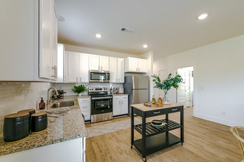 A kitchen with white cabinets and a granite countertop.
