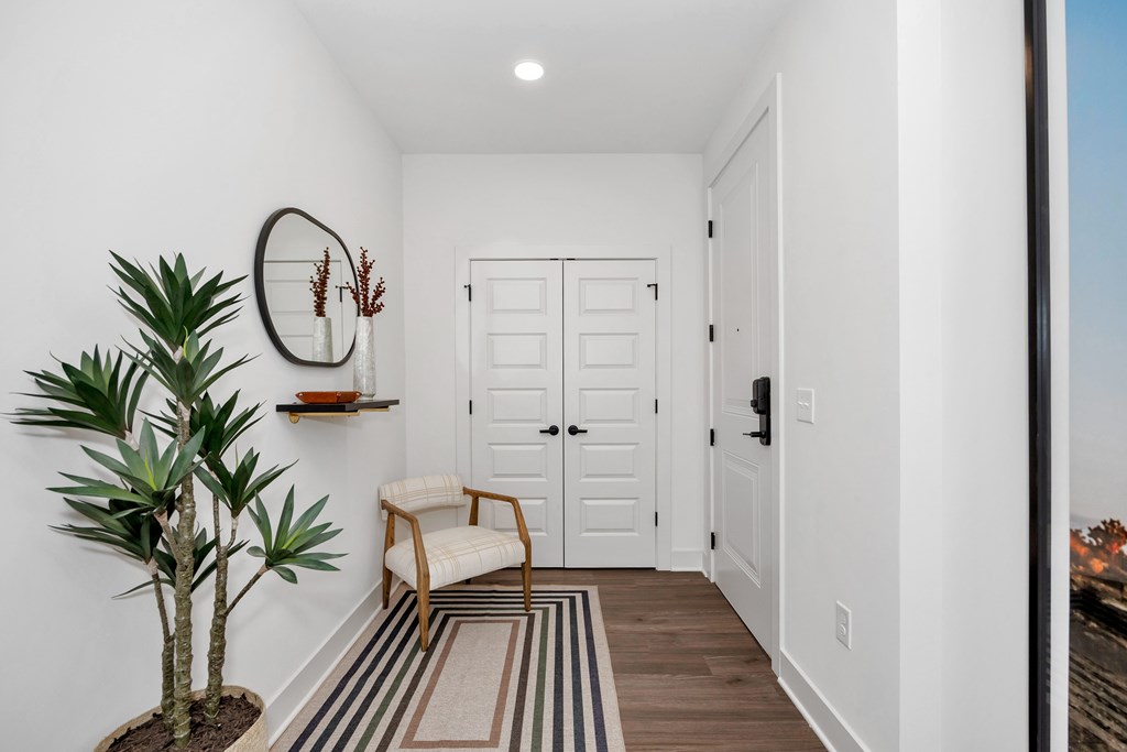 A white hallway with a chair and a plant.