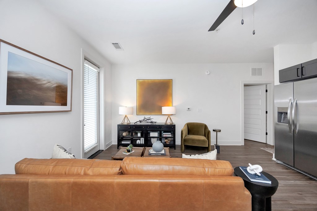 A brown leather couch is in the foreground of a modern living room.