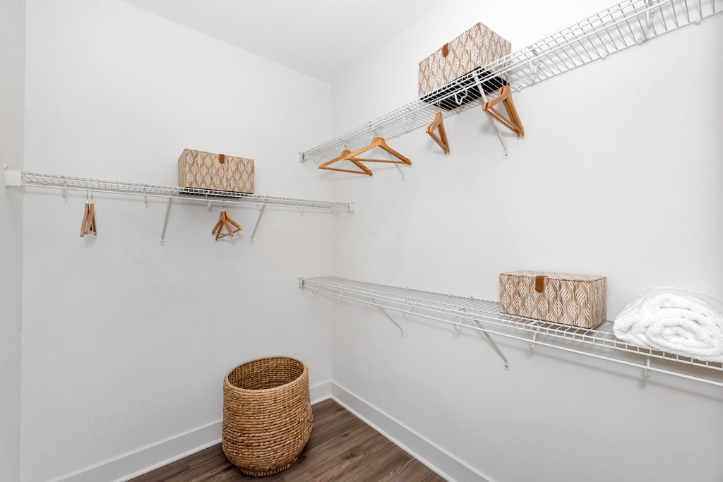 A room with white walls and a white shelving unit with baskets and boxes on it.