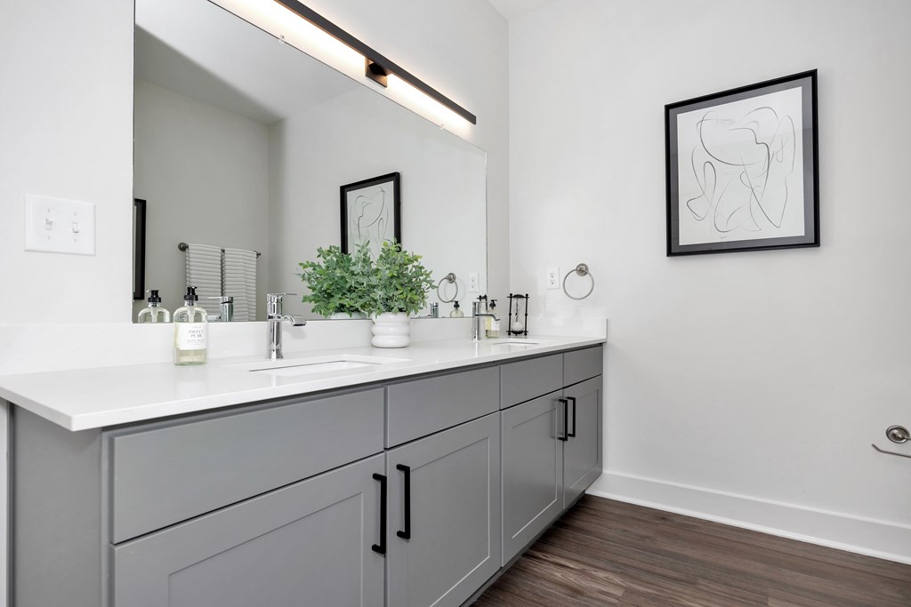 A bathroom with a white countertop and grey cabinets.