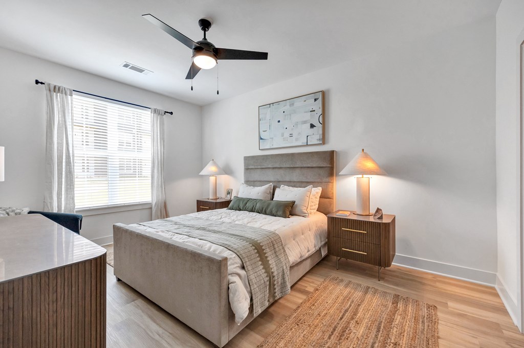 A bedroom with a bed, nightstand, and a ceiling fan.