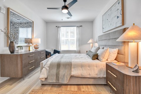 A bedroom with a bed, nightstands, and a ceiling fan.
