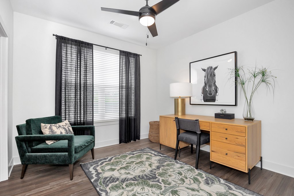 A room with a green chair, a desk, and a rug.