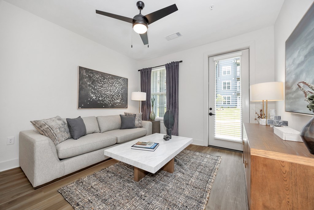 A living room with a couch, a coffee table, and a ceiling fan.
