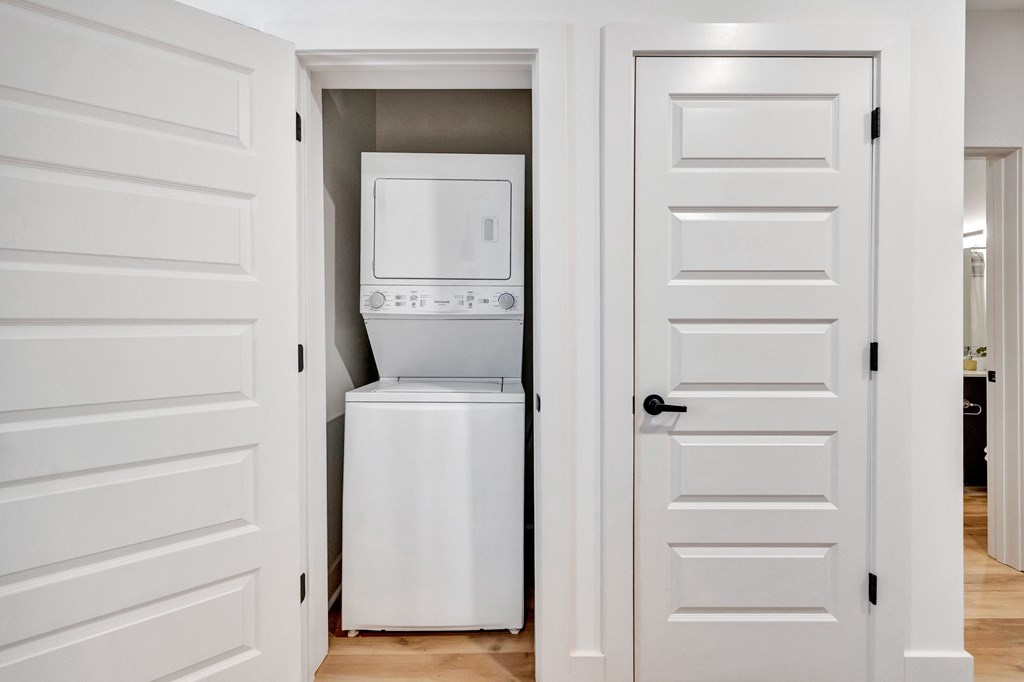 A white door is open to a small kitchen with a white fridge.